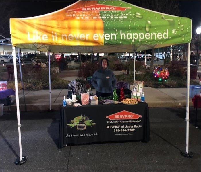 a woman standing behind a table with a SERVPRO tent overhead